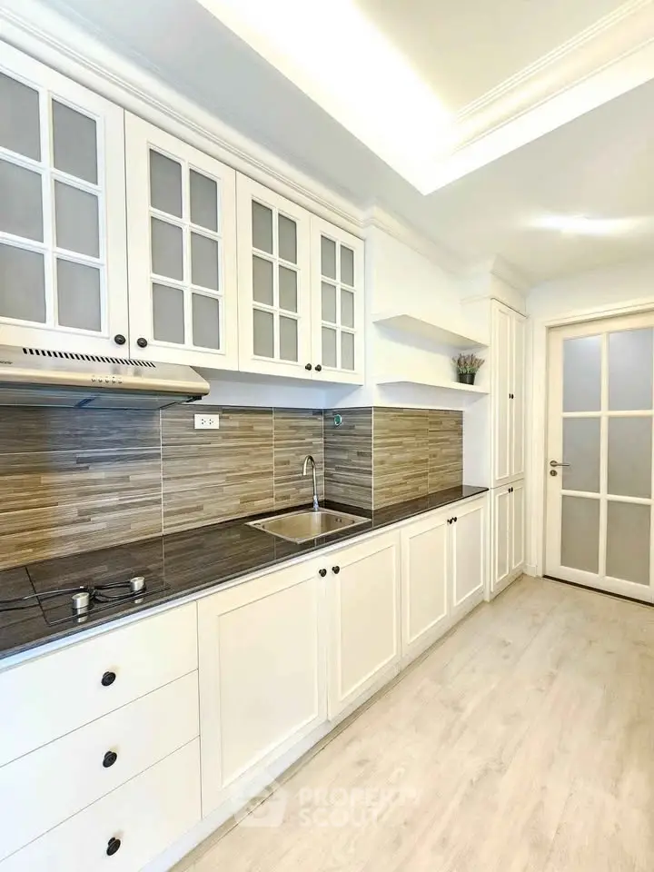 Elegant kitchen with white cabinetry and modern backsplash in a bright interior.