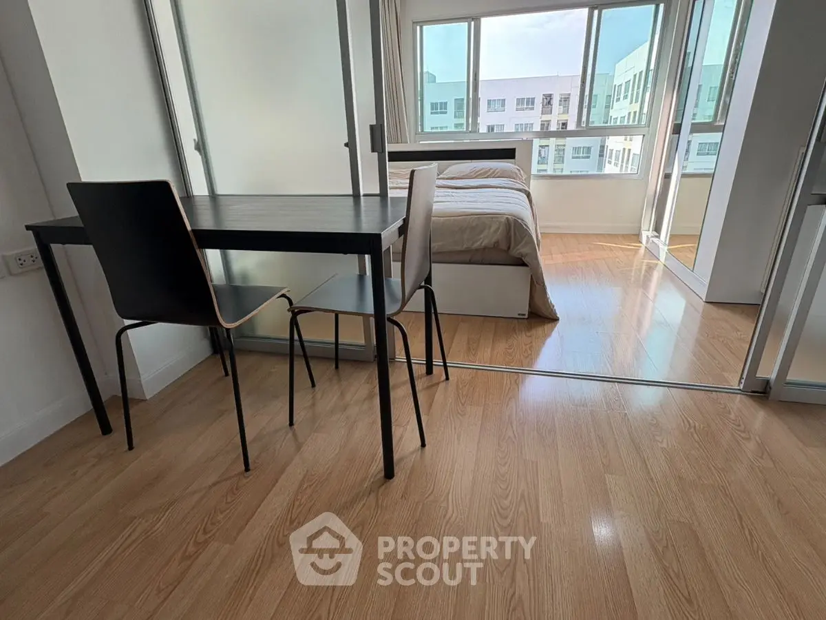 Modern apartment with wooden flooring and glass partition separating bedroom and dining area.