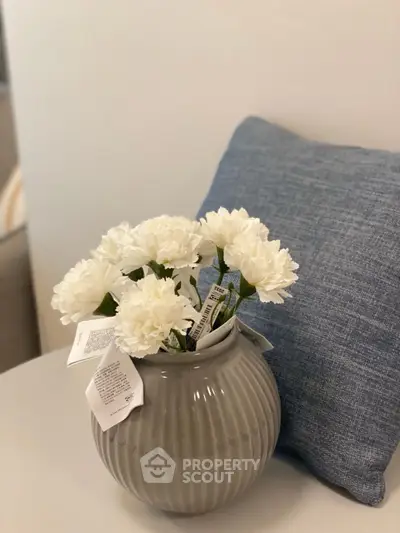 Elegant interior decor with white flowers in a vase and a blue cushion, perfect for modern living spaces.