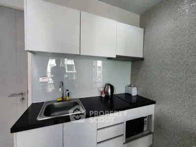 Modern compact kitchen with sleek white cabinets and black countertop
