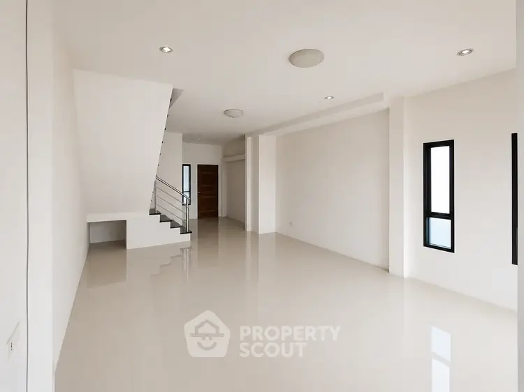 Spacious modern living room with sleek staircase and large windows