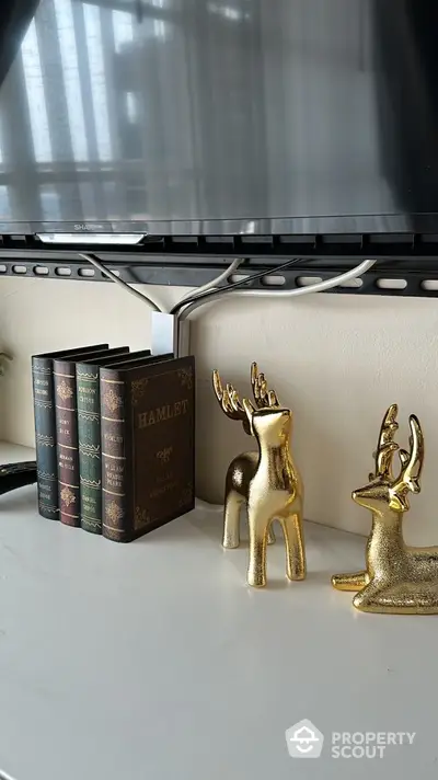 Elegant living room decor with classic books and gold deer figurines on a sleek white shelf.