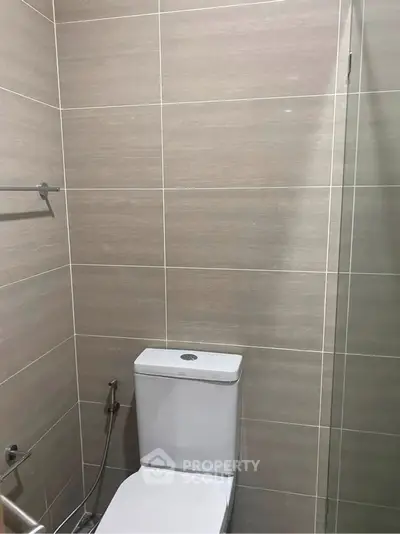 Modern bathroom with sleek tile design and contemporary toilet fixture.