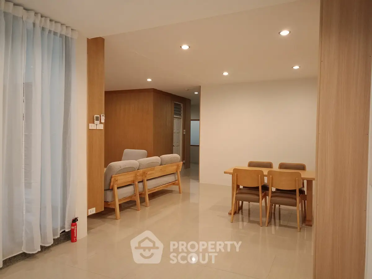 Spacious modern living room with elegant dining area and cozy seating, featuring sleek wooden accents and soft lighting.