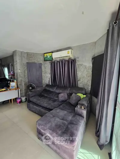 Spacious living room with modern gray sectional sofa and air conditioning, perfect for relaxation.