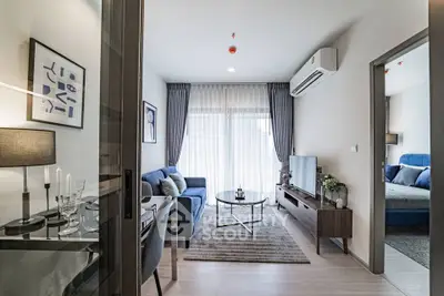 Modern living room with stylish decor and natural light, featuring a cozy sofa and sleek TV unit.