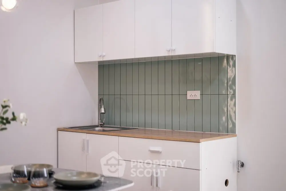 Modern kitchen with sleek white cabinets and stylish green tile backsplash