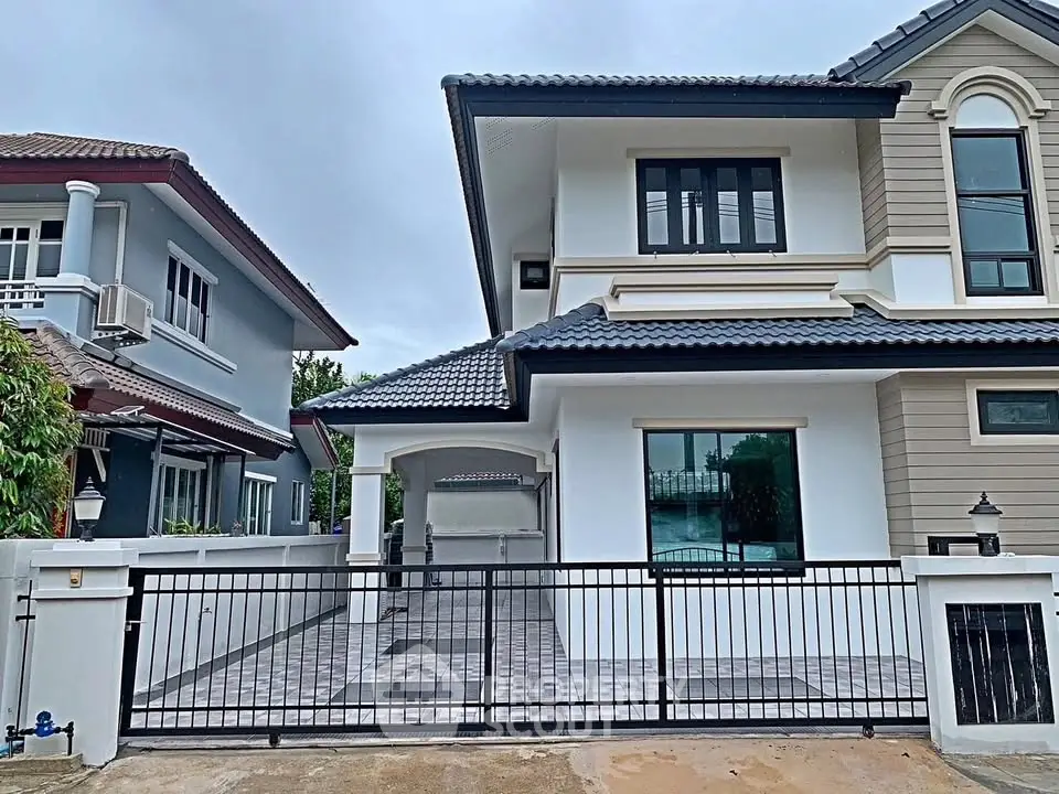 Modern two-story house with stylish facade and gated driveway in a suburban neighborhood.