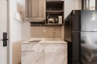 Modern kitchen with sleek cabinetry, induction cooktop, and black refrigerator in a compact layout.