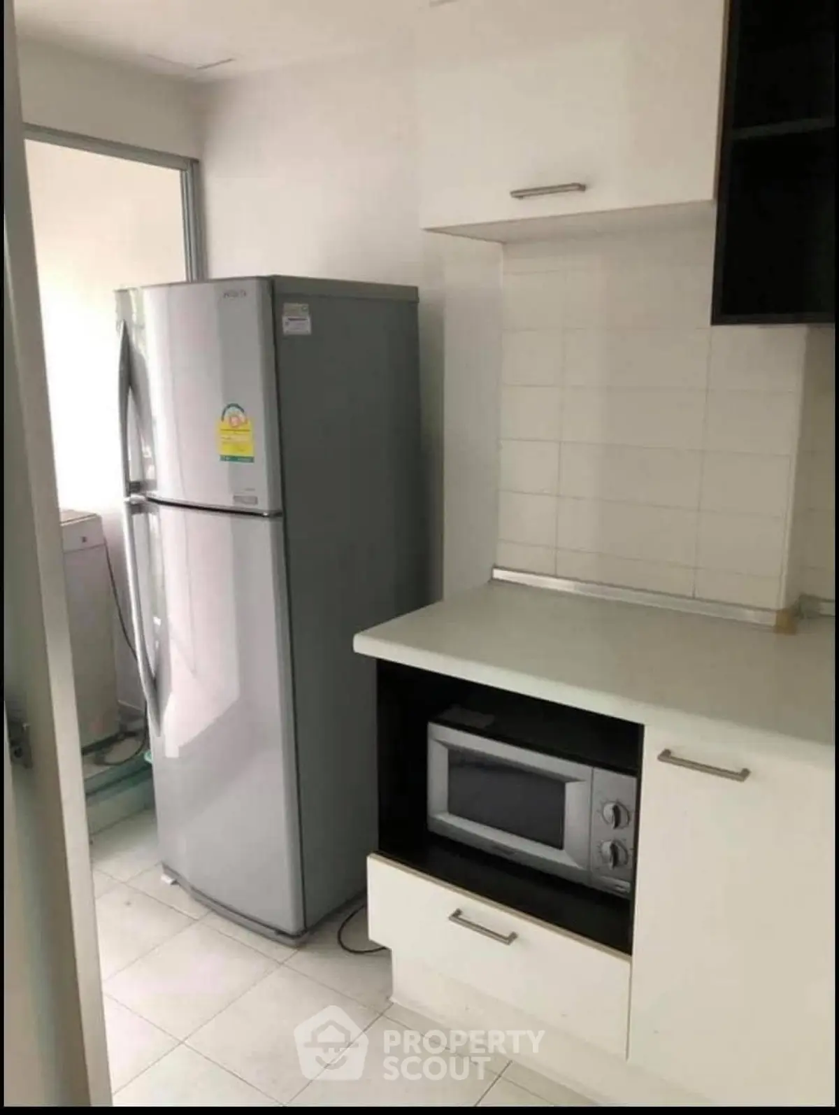 Modern kitchen with sleek fridge and built-in microwave in compact space.