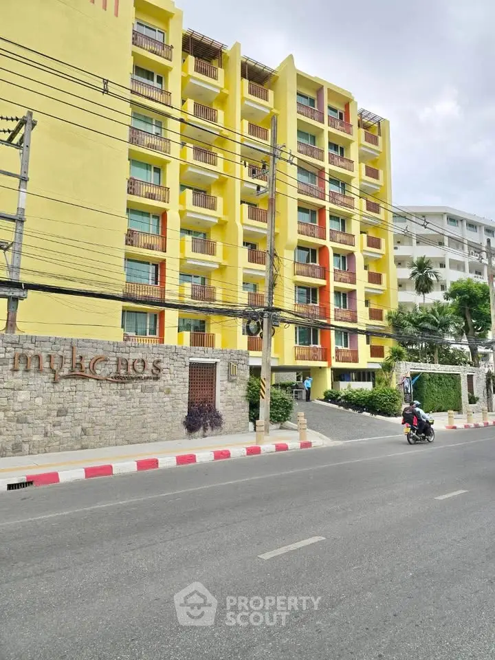 Vibrant yellow apartment building with modern design and lush greenery