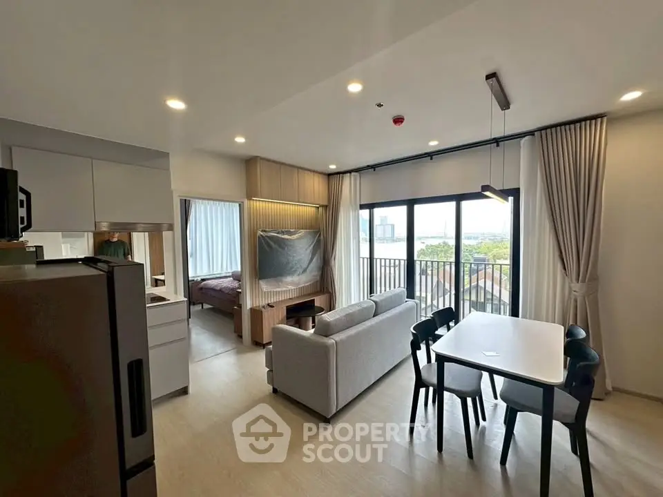 Modern open-plan living room with dining area and balcony view in a stylish apartment.