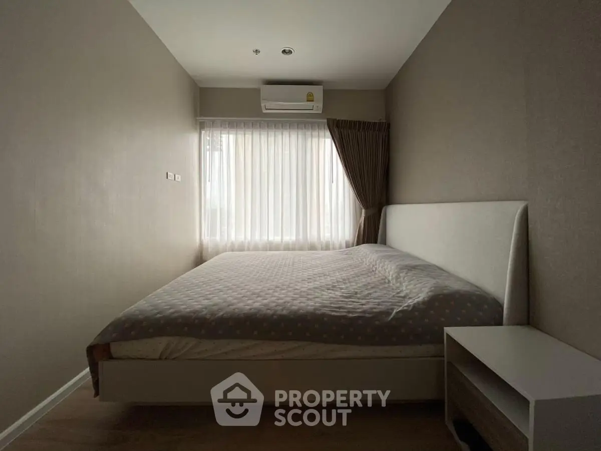 Cozy bedroom with modern design, featuring a large bed and natural light from a window.