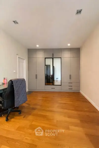 Spacious bedroom with modern wardrobe and wooden flooring