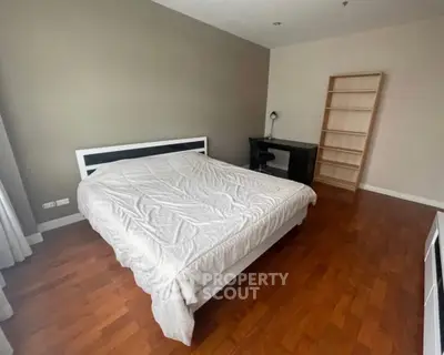 Spacious bedroom with wooden flooring and modern furniture