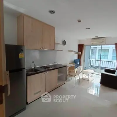 Modern open-plan living room with kitchenette and balcony view