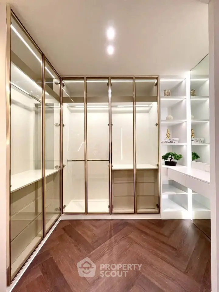 Luxurious walk-in closet with elegant glass doors and modern shelving.