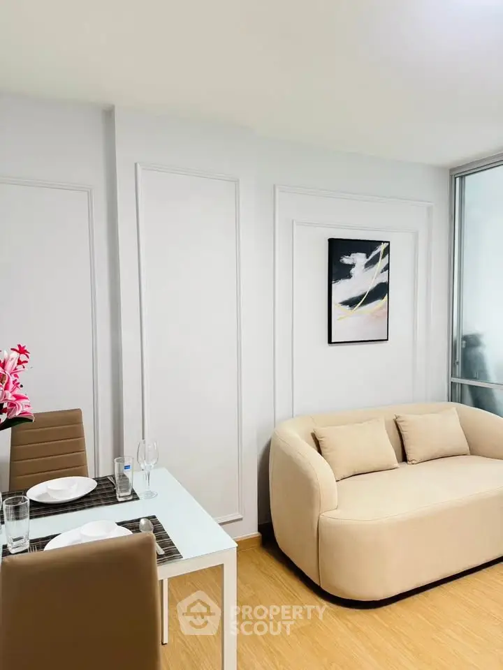 Modern living room with stylish beige sofa and dining area, featuring elegant decor and bright ambiance.