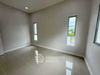 Spacious empty room with glossy tiled floor and large windows for natural light.
