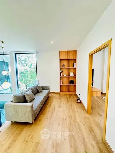 Modern living room with wooden flooring and large windows offering natural light.