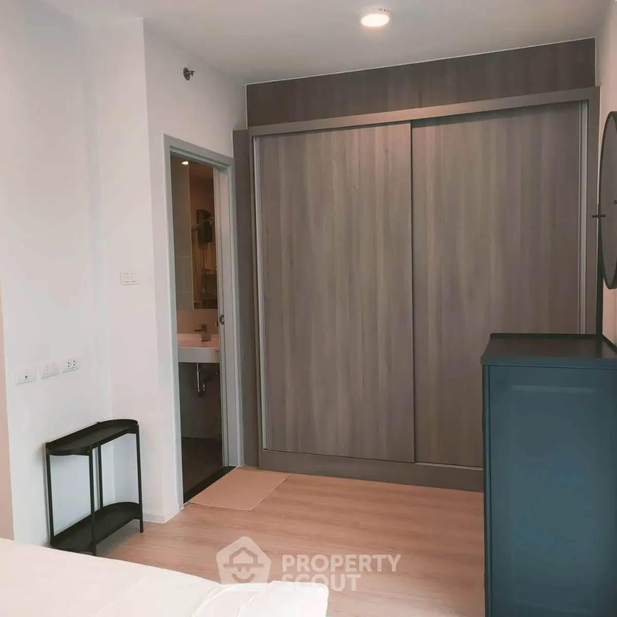 Modern bedroom with sleek wardrobe and en-suite bathroom in stylish apartment.