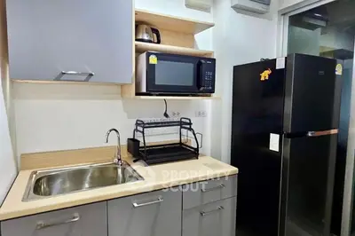 Modern kitchen with sleek cabinets, stainless steel sink, and black refrigerator