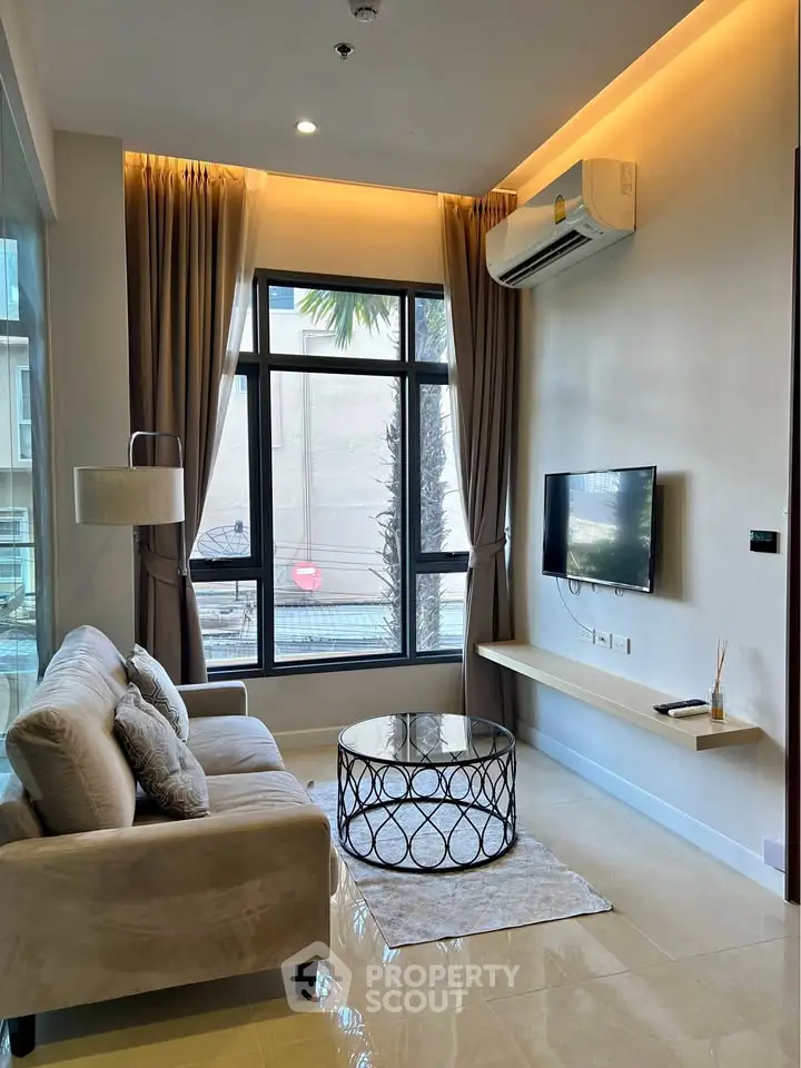 Modern living room with stylish decor and large window offering natural light.