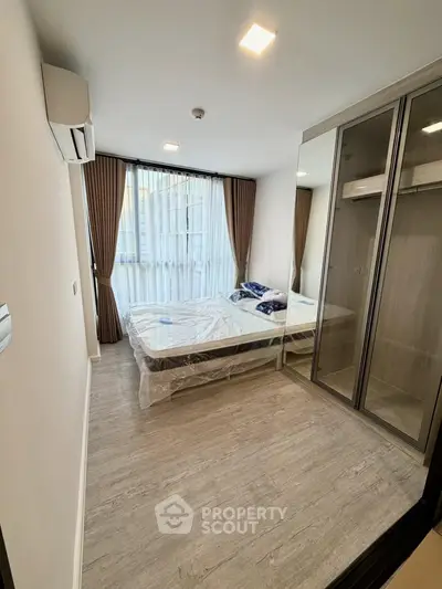 Modern bedroom with large window and mirrored wardrobe in stylish apartment