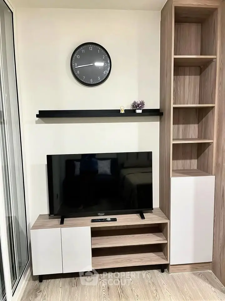 Modern living room with sleek TV stand, wall clock, and stylish shelving unit.