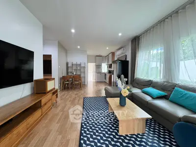 Spacious living room with modern decor and open layout, featuring a cozy seating area and large TV.