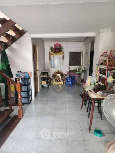 Spacious living area with tiled flooring and wooden staircase, ideal for cozy family gatherings.