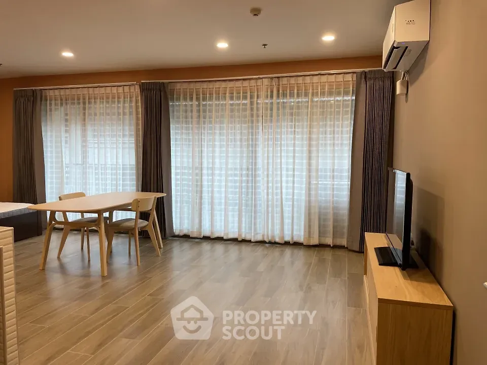 Spacious modern living room with large windows and elegant wooden flooring.