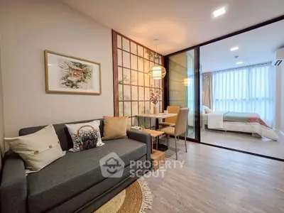 Modern living room with cozy sofa and dining area, adjacent to a stylish bedroom with natural light.