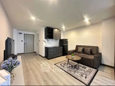 Modern living room with sleek kitchen, stylish sofa, and elegant decor in a contemporary apartment.