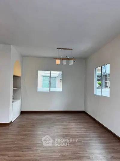 Spacious empty room with wooden flooring and modern lighting, ideal for customization.