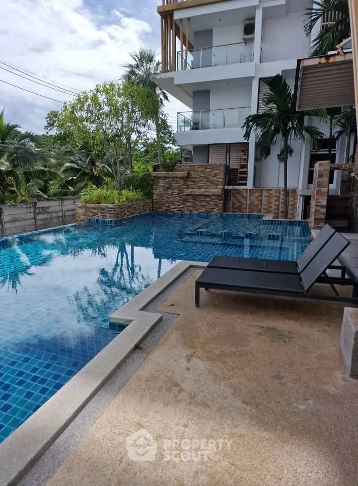 Luxurious poolside view at modern apartment complex with lush greenery and stylish architecture.