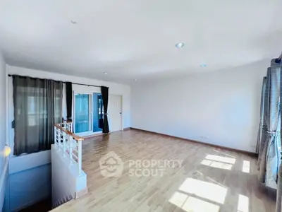 Spacious sunlit living room with wooden flooring and large windows