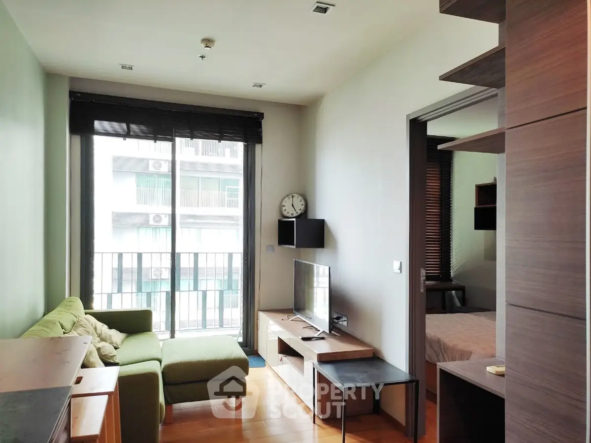 Modern living room with green sofa and large window in stylish apartment