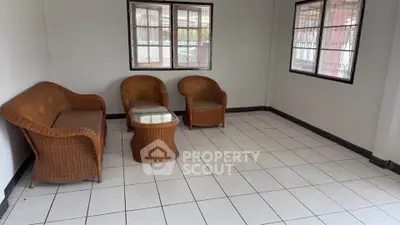 Spacious tiled living room with wicker furniture and large windows.
