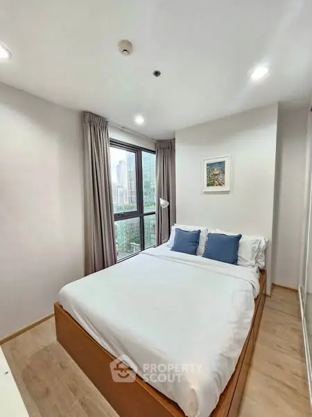 Modern bedroom with city view, featuring cozy bed and stylish decor in high-rise apartment.