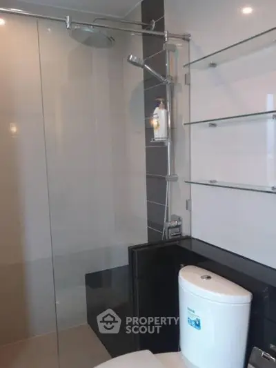 Modern bathroom with sleek shower and glass shelves in a contemporary apartment.