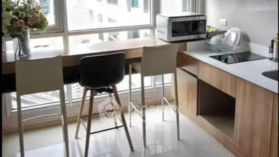 Modern kitchen with sleek countertops and city view, featuring a breakfast bar and stylish seating.