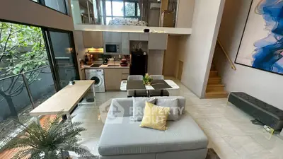 Modern loft apartment with open living area, stylish kitchen, and large windows overlooking greenery.