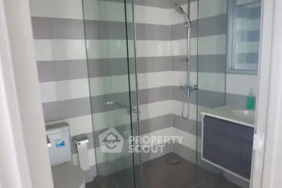 Modern bathroom with glass shower and sleek fixtures in contemporary home.