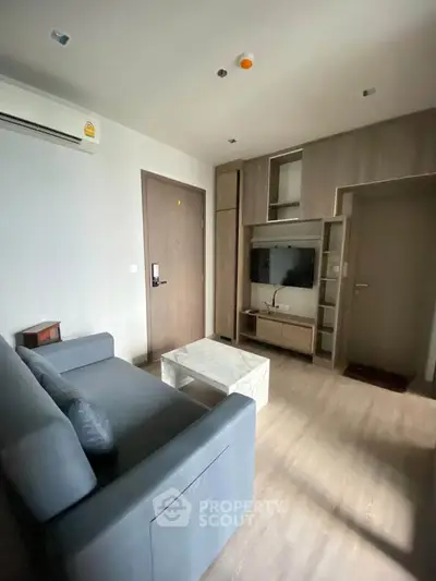 Modern living room with sleek furniture and built-in TV unit in a cozy apartment.