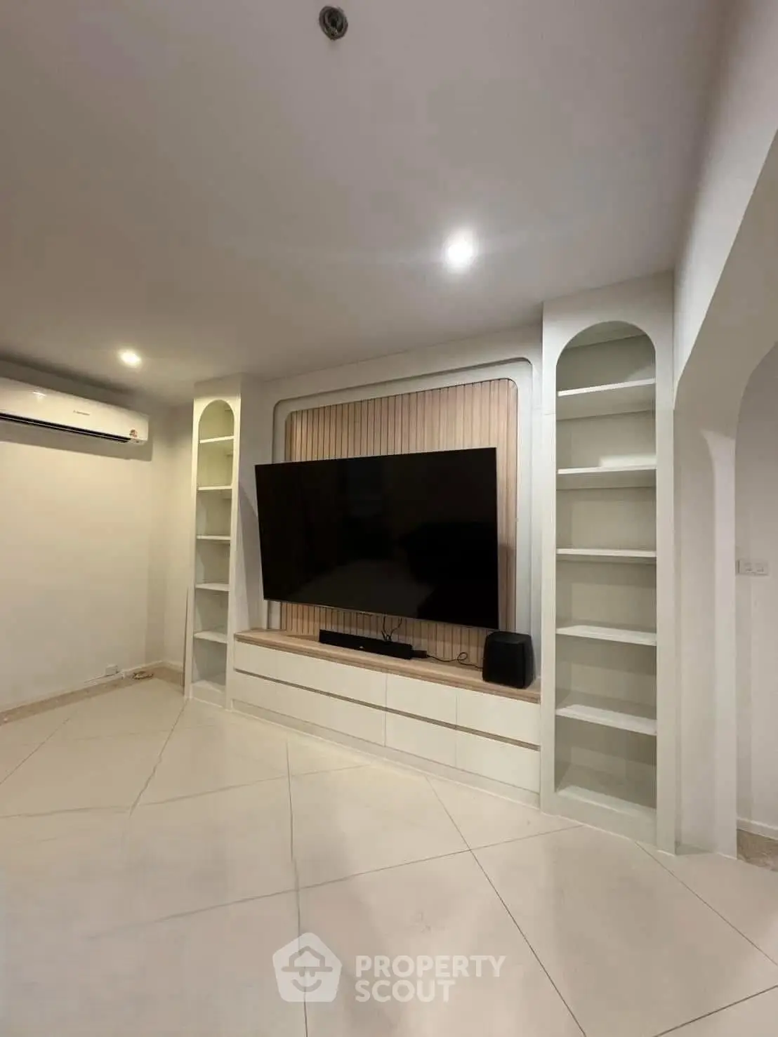 Modern living room with built-in shelves and large TV, perfect for entertainment.