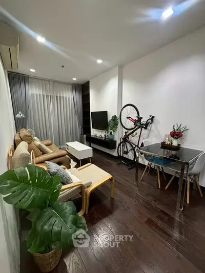 Modern living room with cozy seating and stylish decor, featuring a bicycle and indoor plants.