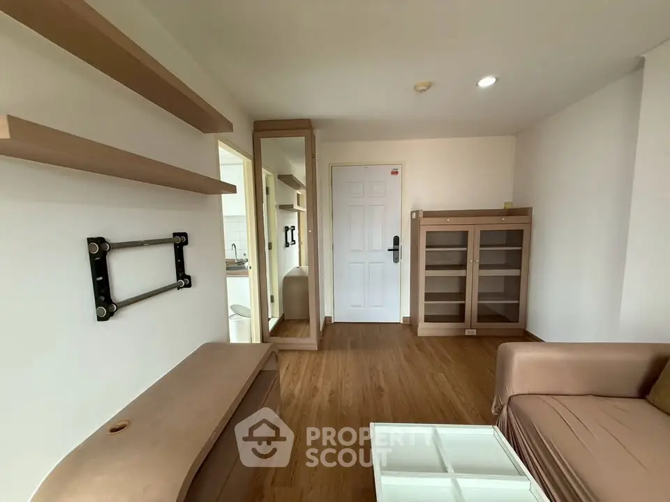 Modern living room with wooden flooring, wall-mounted shelves, and a sleek sofa in a cozy apartment.