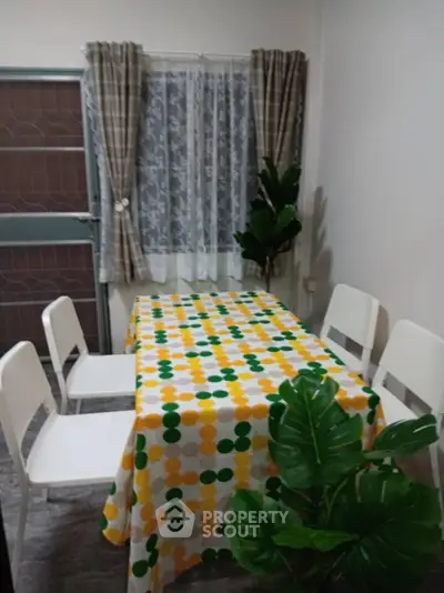 Cozy dining area with colorful tablecloth and modern white chairs
