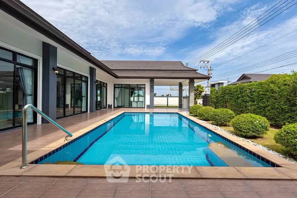 Luxurious modern home with private pool and spacious patio under clear blue skies.